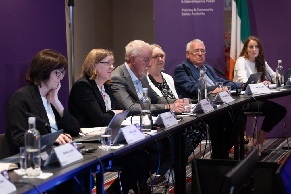 Members of the PCSA Authority sit at a table with purple banners in the background