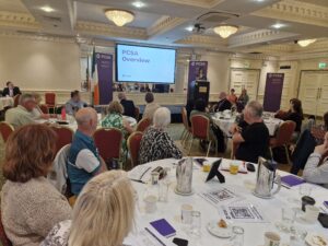 A woman addresses a room full of people