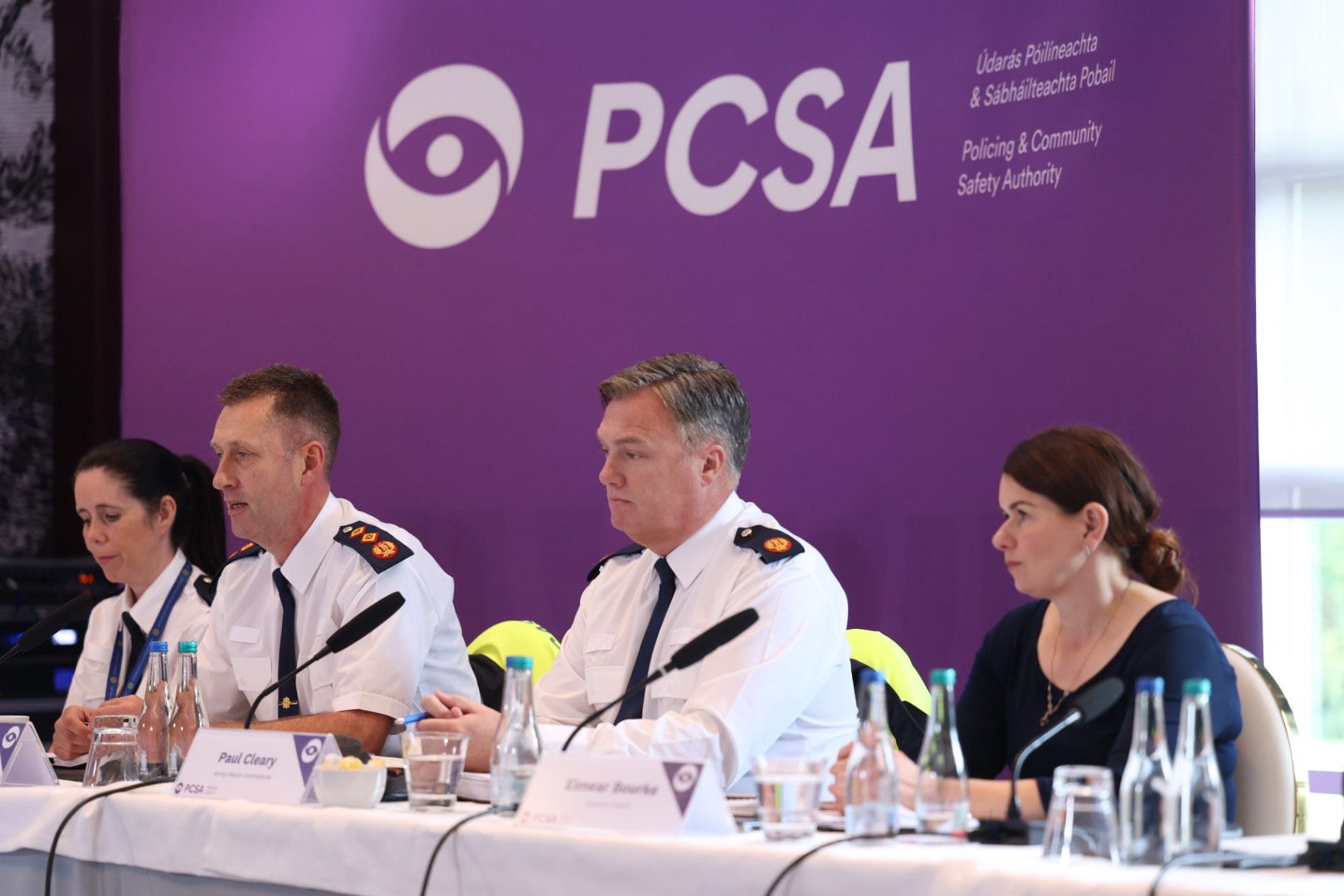 Senior garda officers sit at a table in front of a purple PCSA banner