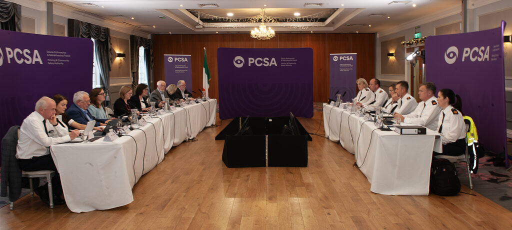 A meeting room with two long tables and two rows of people facing each other