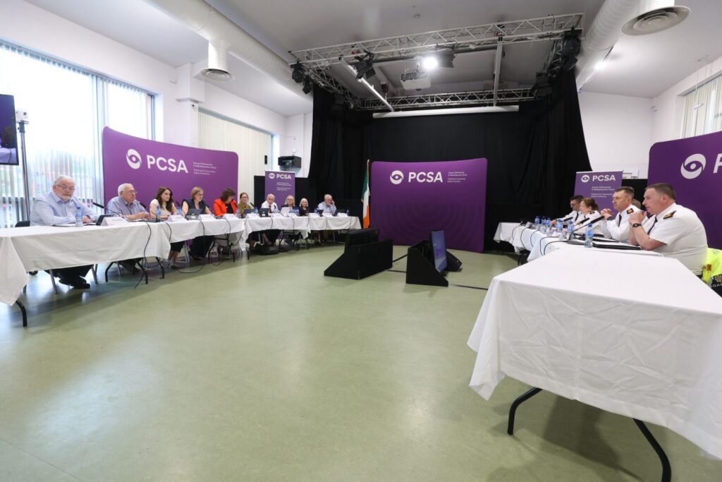 Two long tables with white covers are situated opposite each other, with people sitting at each table